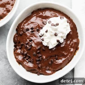 Plant-Based Pudding Perfection 5 chocolate pudding in a white bowl topped with chocolate chips and whipped cream
