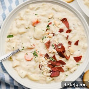 A square image of a bowl of creamy soup with crispy vegan bacon pieces on top, ready to be enjoyed.