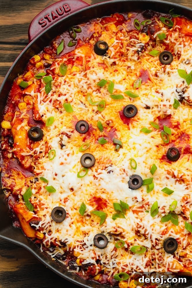 A vibrant pan full of vegan skillet enchiladas, generously topped with melted cheese and sliced black olives, ready to be served.
