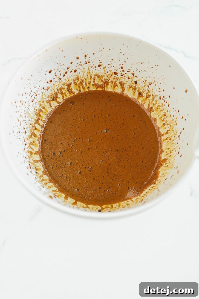 Cloud Coffee 5 Light brown liquid in a large white bowl being whipped by a hand mixer