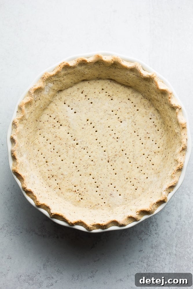 Cooked pie crust on a grey background with fork holes, ready for filling.