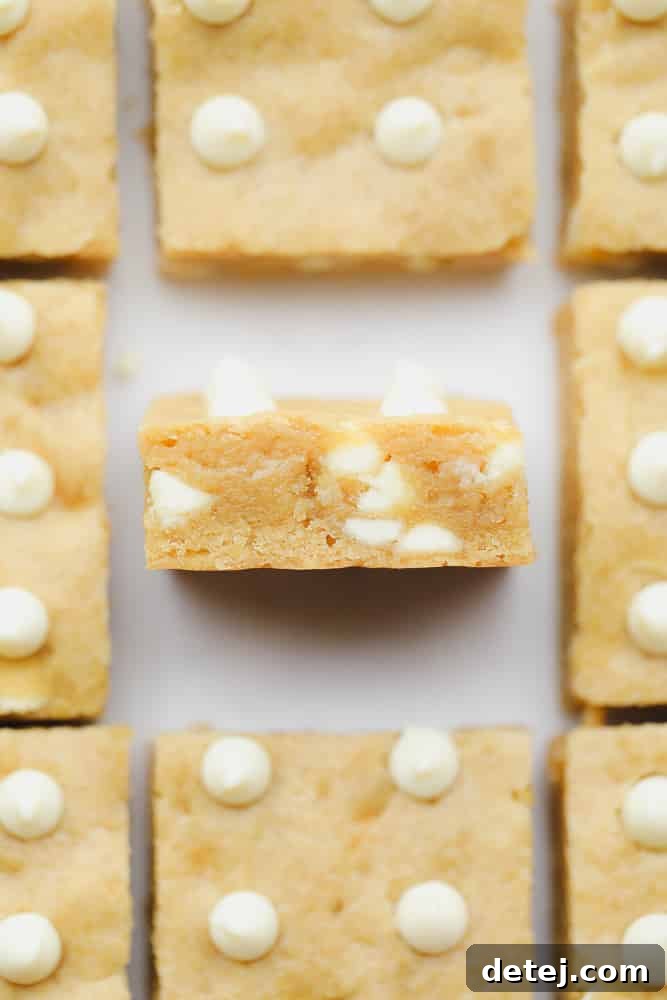 Baked blondies with white chocolate chips cut into squares, showcasing their golden-brown edges and gooey interior