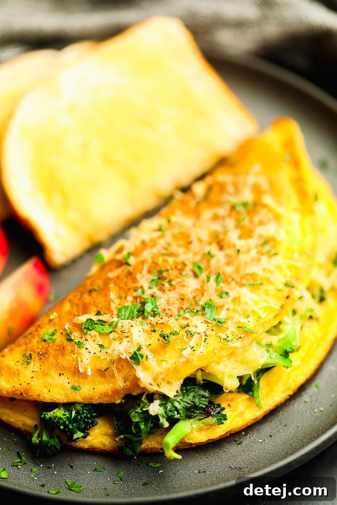 Close up of a perfectly cooked vegan omelette filled with fresh vegetables, served on a modern grey plate.