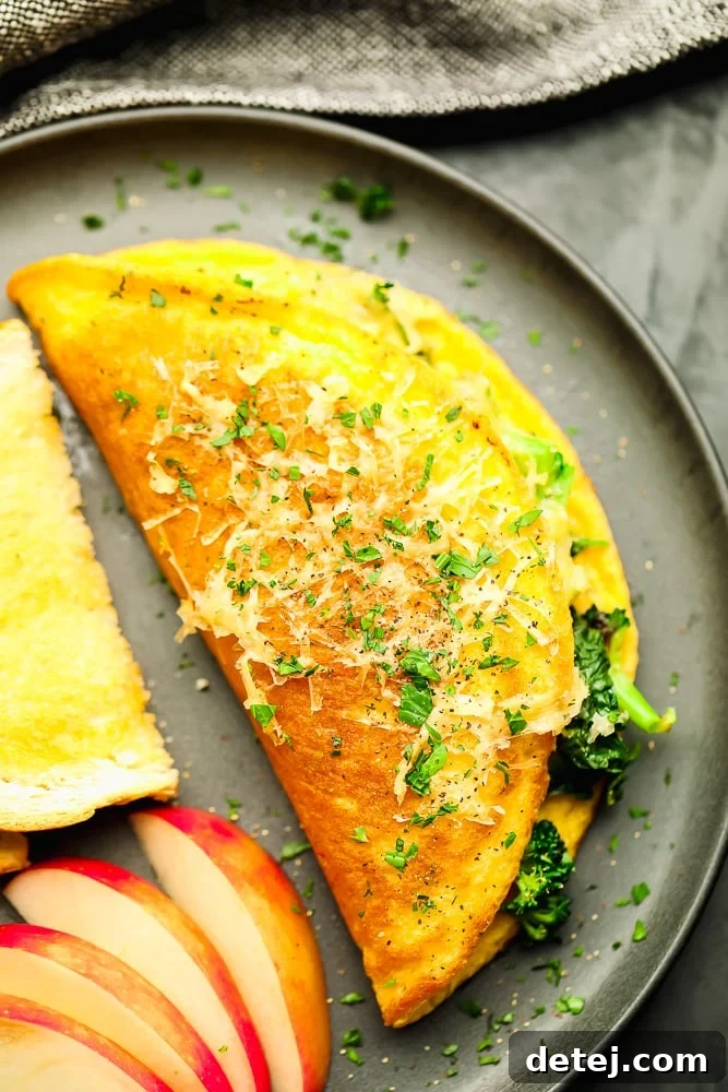 A vegan omelette filled with vegetables, served on a grey plate with a side of fresh fruit and toasted bread.