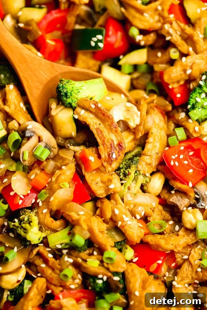 close up on a wooden spoon scooping vegetables and soy curls from a stir fry, showing texture and vibrant colors