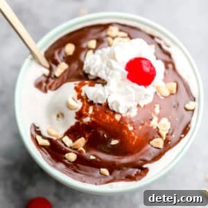 Square image of vegan vanilla ice cream with hot fudge, coconut whipped cream and a cherry topping.