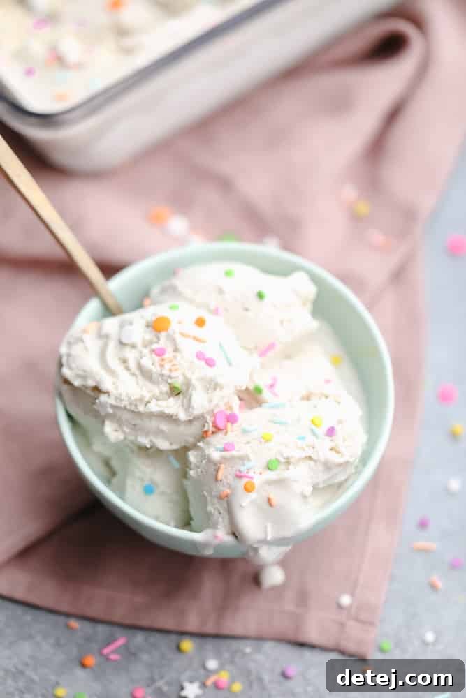 A vibrant teal bowl filled with scoops of vanilla vegan ice cream, generously topped with an array of colorful sprinkles.