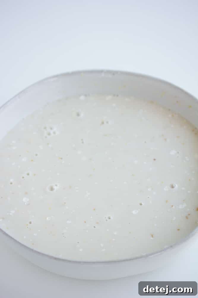 A bowl containing a white liquid mixture, representing the wet ingredients for dipping tofu nuggets.