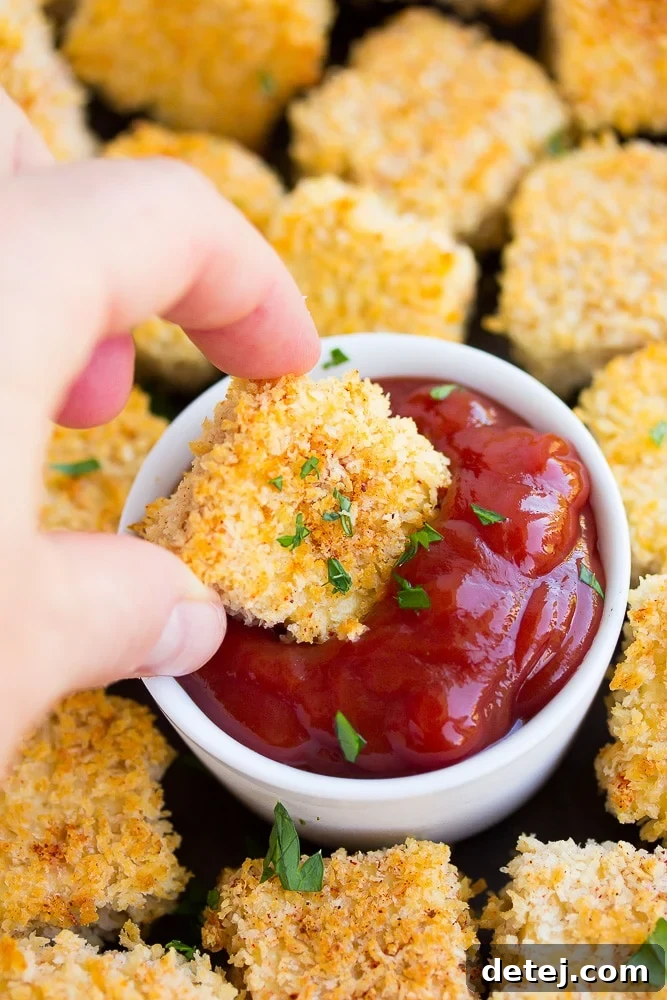 A single crispy tofu nugget being dipped into a bowl of ketchup, highlighting its golden brown exterior.