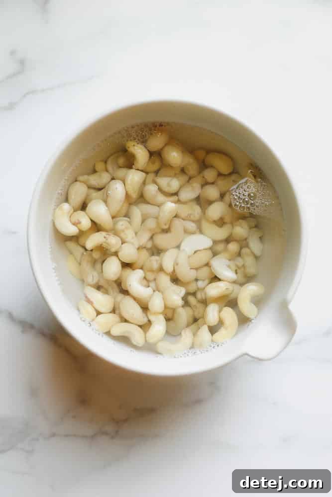 Raw cashews soaking in a bowl of water, preparing for blending into cream.