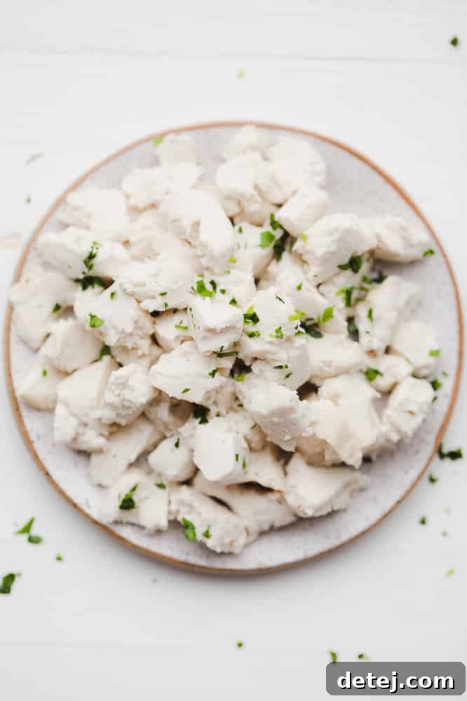 crumbled white cubes of vegan feta cheese topped with fresh green herbs on a white plate