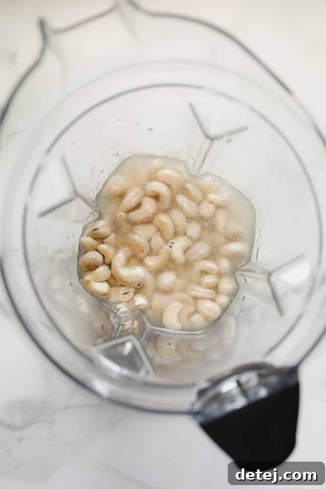 overhead view of raw cashews and water in a blender, ready for blending