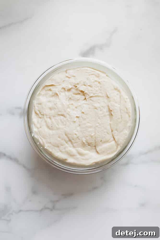 a smooth white vegan feta mixture setting in a glass jar