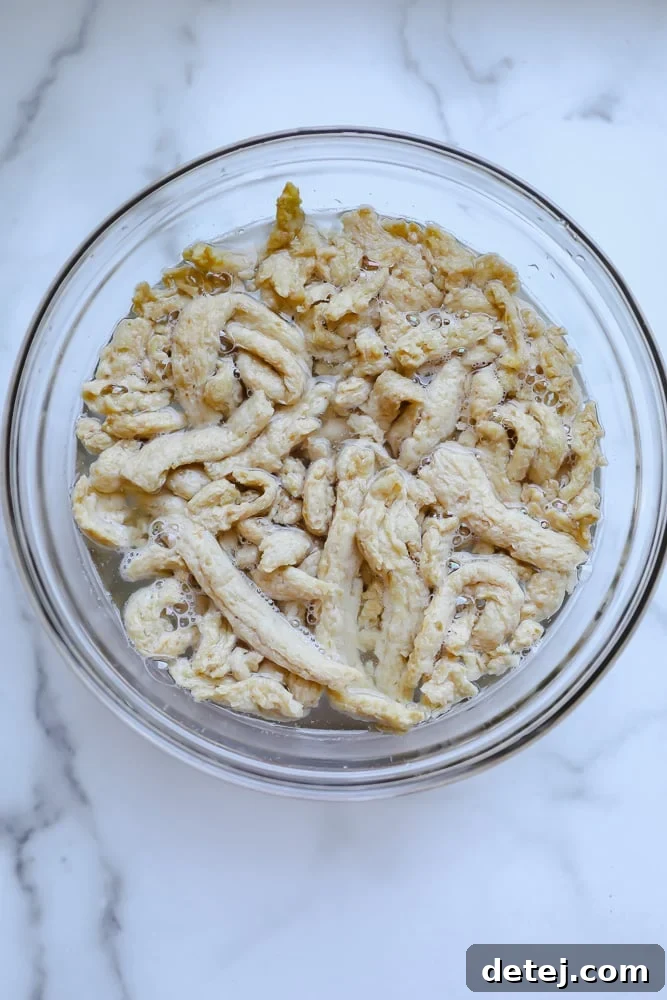 Soy curls soaking in a bowl of warm water, expanding and softening as they rehydrate, preparing for the flavorful marinade.
