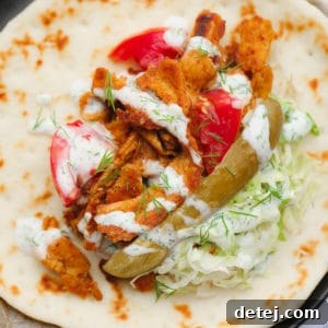 a pile of lettuce, pickles, seasoned soy curls, and tomatoes sitting in the middle of a round piece of bread.