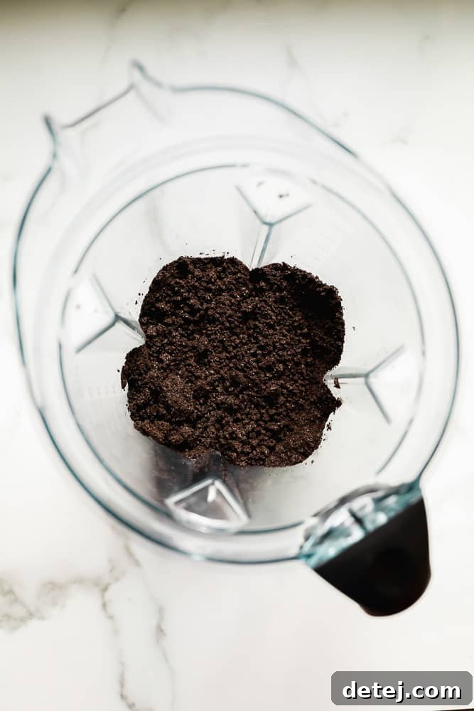 Close-up of dark brown crumbled cookies ready for the crust, inside a blender.