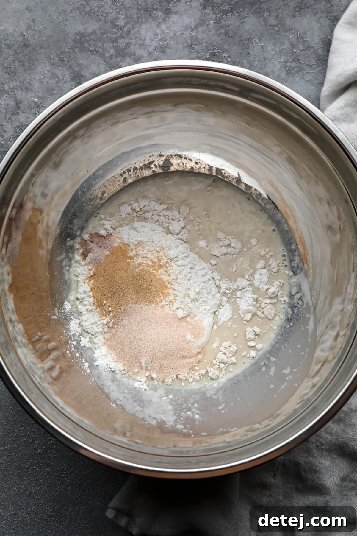 silver bowl with flour and spices and milk in it, not mixed