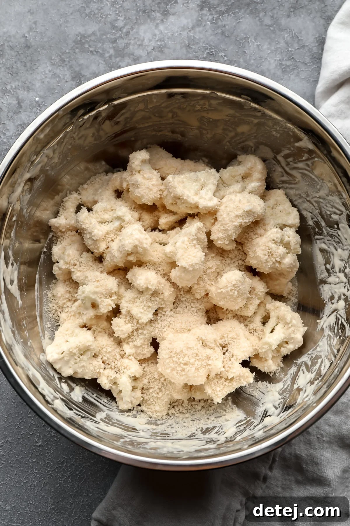 cauliflower florets mixed with flour mixture and breadcrumbs in silver bowl