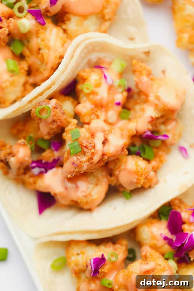 fried cauliflower with orange sauce, purple cabbage, and green herbs in a flour tortilla