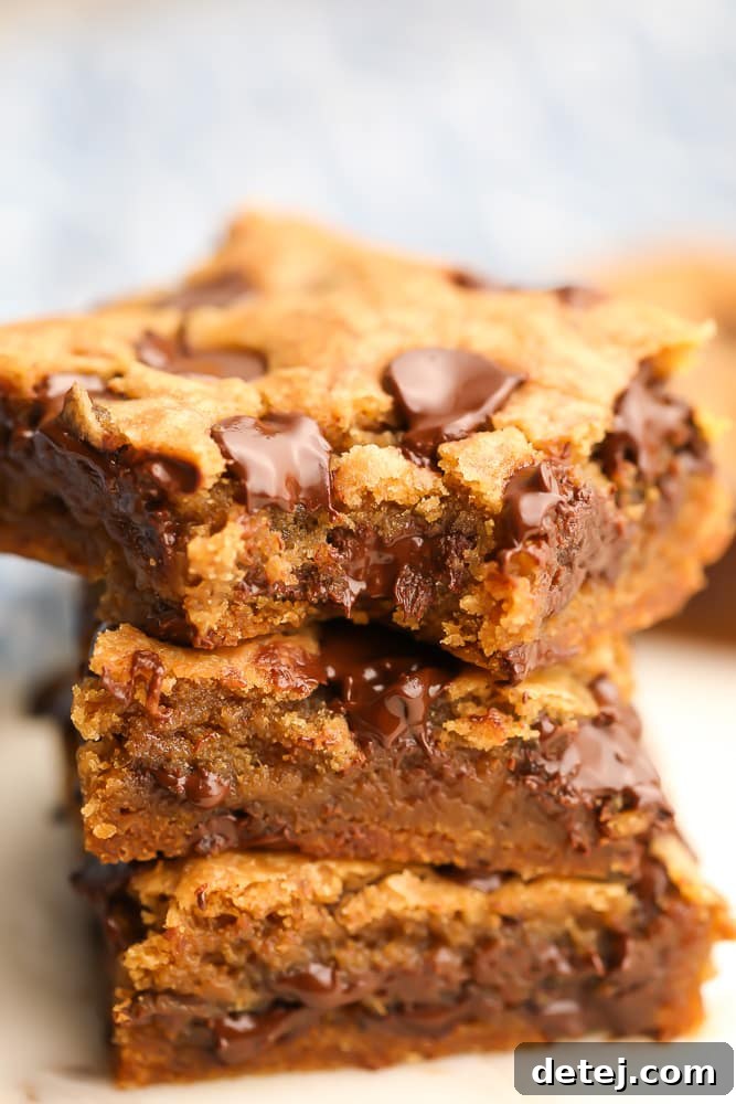 A close-up of a vegan chocolate chip cookie bar with a bite taken out, showing its soft, chewy interior and abundant chocolate chips.
