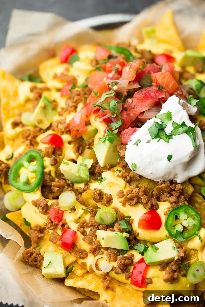 A close-up shot of a perfectly assembled serving of vegan nachos, showcasing layers of crispy chips, melted cheese, and fresh toppings.