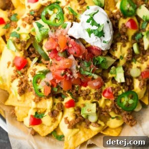Square image of ultimate vegan nachos on a plate with parchment paper.