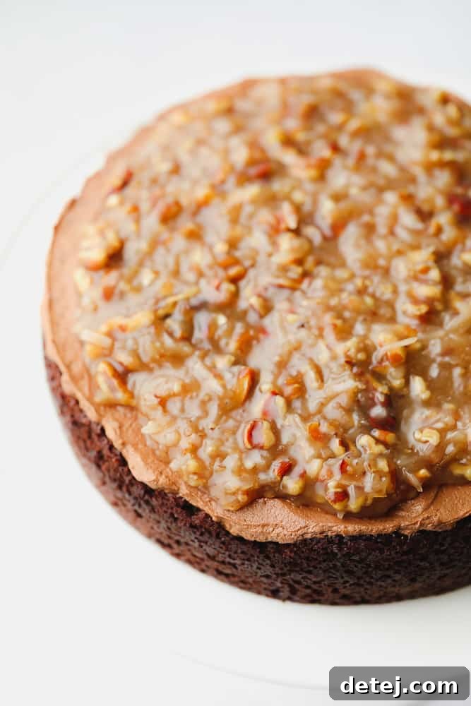 A layered vegan chocolate cake with chocolate frosting and a generous helping of pecan caramel sauce on top.
