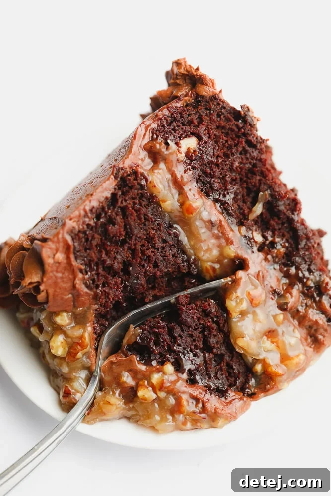 A fork cutting into a freshly sliced piece of frosted chocolate cake, revealing its moist layers and filling.