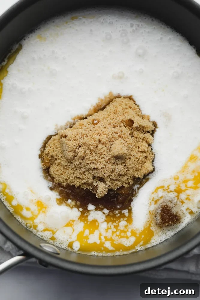 Milk, vegan butter, and brown sugar simmering in a black saucepan to create the caramel base.