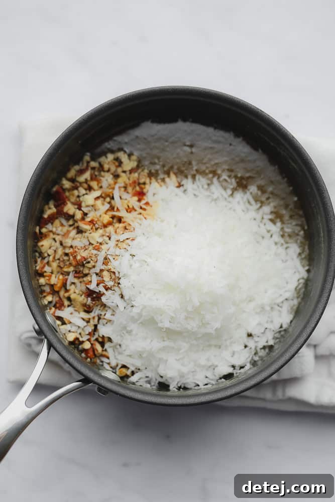Coconut shreds and chopped pecans being stirred into the warm caramel sauce in a black saucepan.