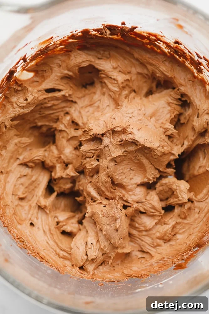 Perfectly whipped, fluffy vegan chocolate frosting in a clear glass bowl, ready for assembly.