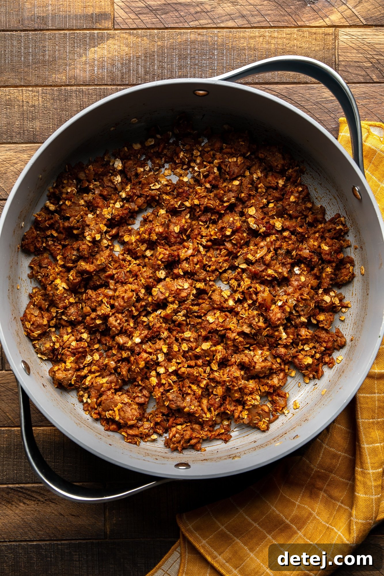 Cooking the savory vegan beef and onion filling for a vegan wellington in a large skillet.