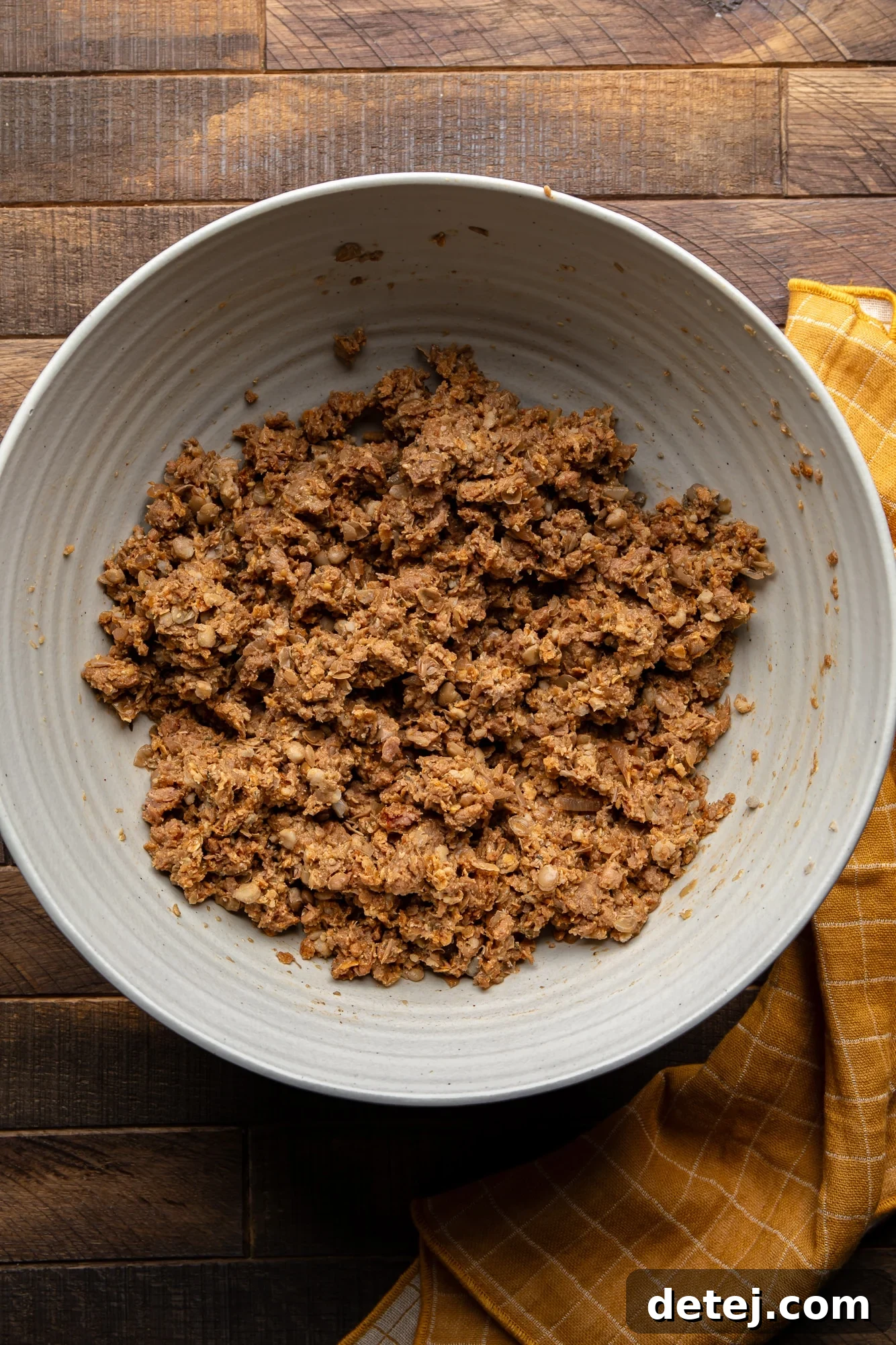 The well-combined vegan wellington filling, featuring mashed lentils and savory vegan beef, in a large grey bowl.