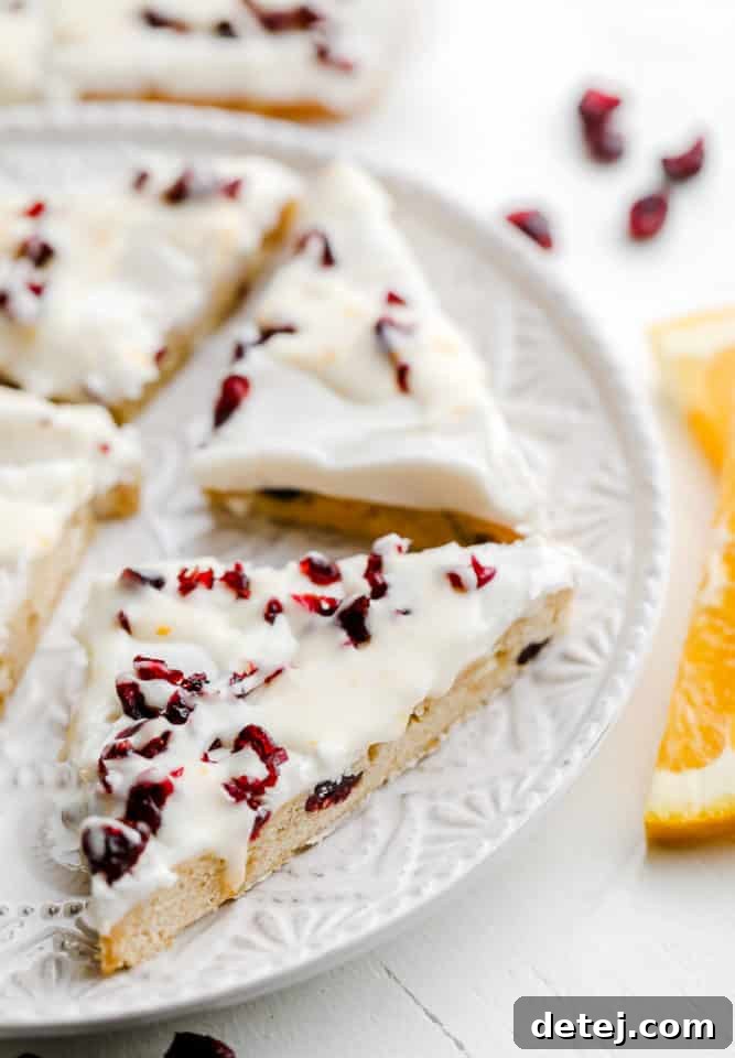 close up on vegan cranberry bliss bars cut into triangles on a white plate.