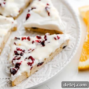 close up on vegan cranberry bliss bars cut into triangles on a white plate.