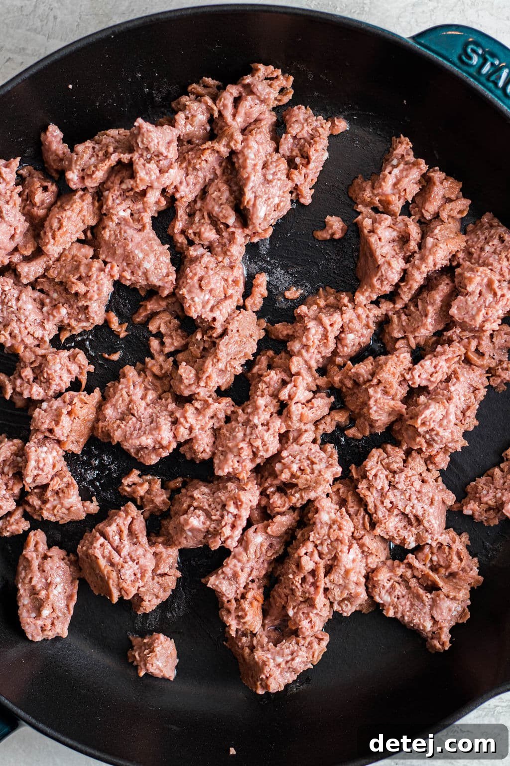 raw vegan ground beef cooking in a black skillet.
