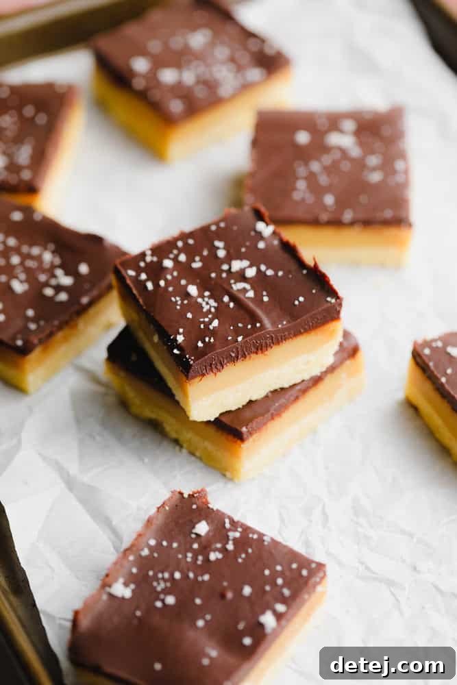 Several vegan millionaire shortbread bars neatly cut into small squares and arranged on a serving tray.