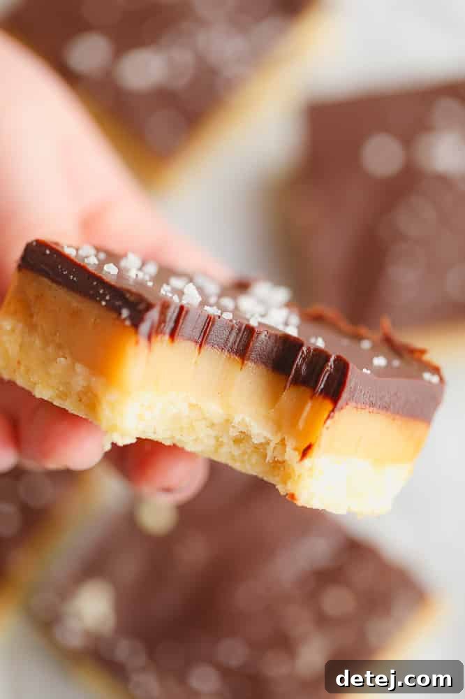 A vibrant close-up of a Vegan Millionaire Shortbread bar with a perfect bite taken, highlighting the rich, gooey caramel and crisp shortbread.