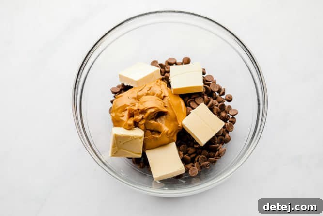 A microwave-safe bowl containing vegan chocolate chips, creamy peanut butter, and vegan butter, ready to be melted together for the muddy buddies coating.