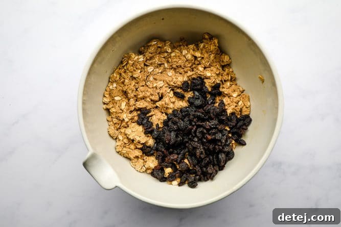 Oatmeal cookie dough with raisins fully mixed in a bowl, showcasing the moist, thick consistency, ready for scooping.