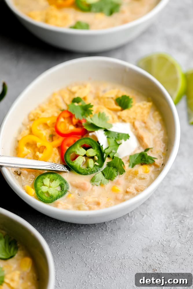 A close-up shot of creamy vegan white chili, beautifully garnished with fresh jalapeños, cilantro, and a dollop of vegan sour cream, highlighting its inviting texture.