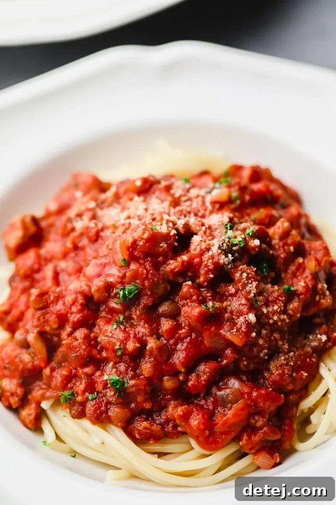 Ultimate Plant-Based Spaghetti 3 A close-up view of spaghetti noodles generously covered with rich, homemade vegan spaghetti sauce in a white bowl.