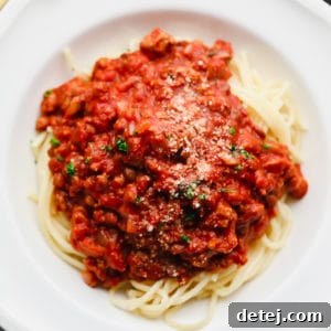 A close-up view of spaghetti noodles generously covered with rich, homemade vegan spaghetti sauce in a white bowl.