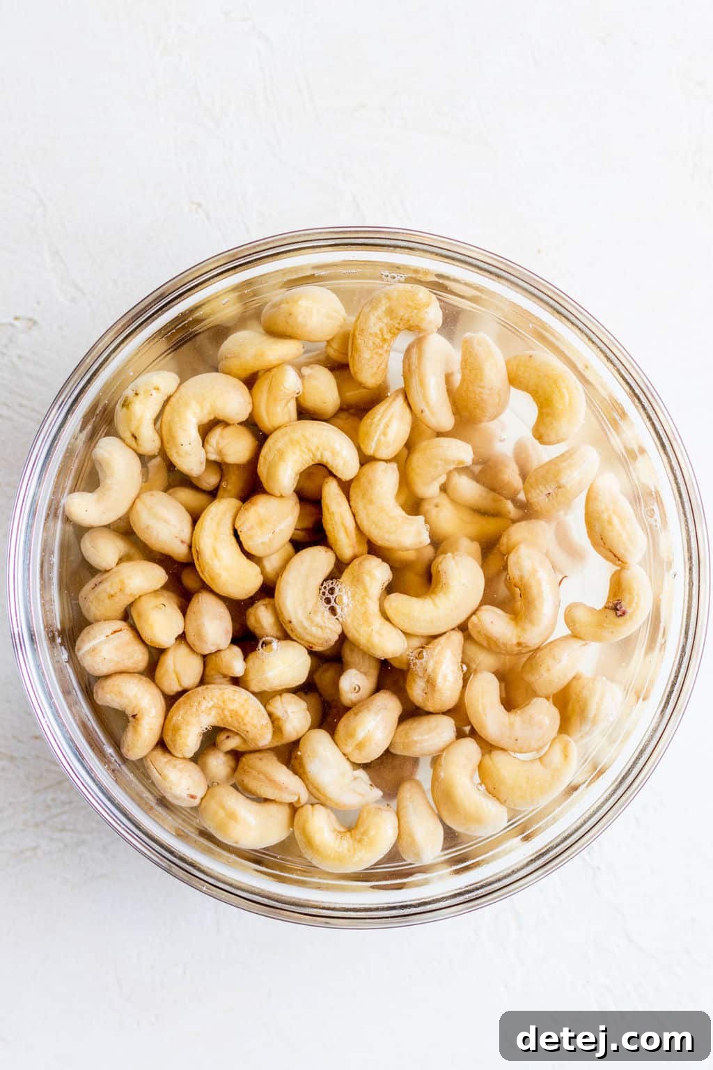 cashews submerged in water in a glass bowl.