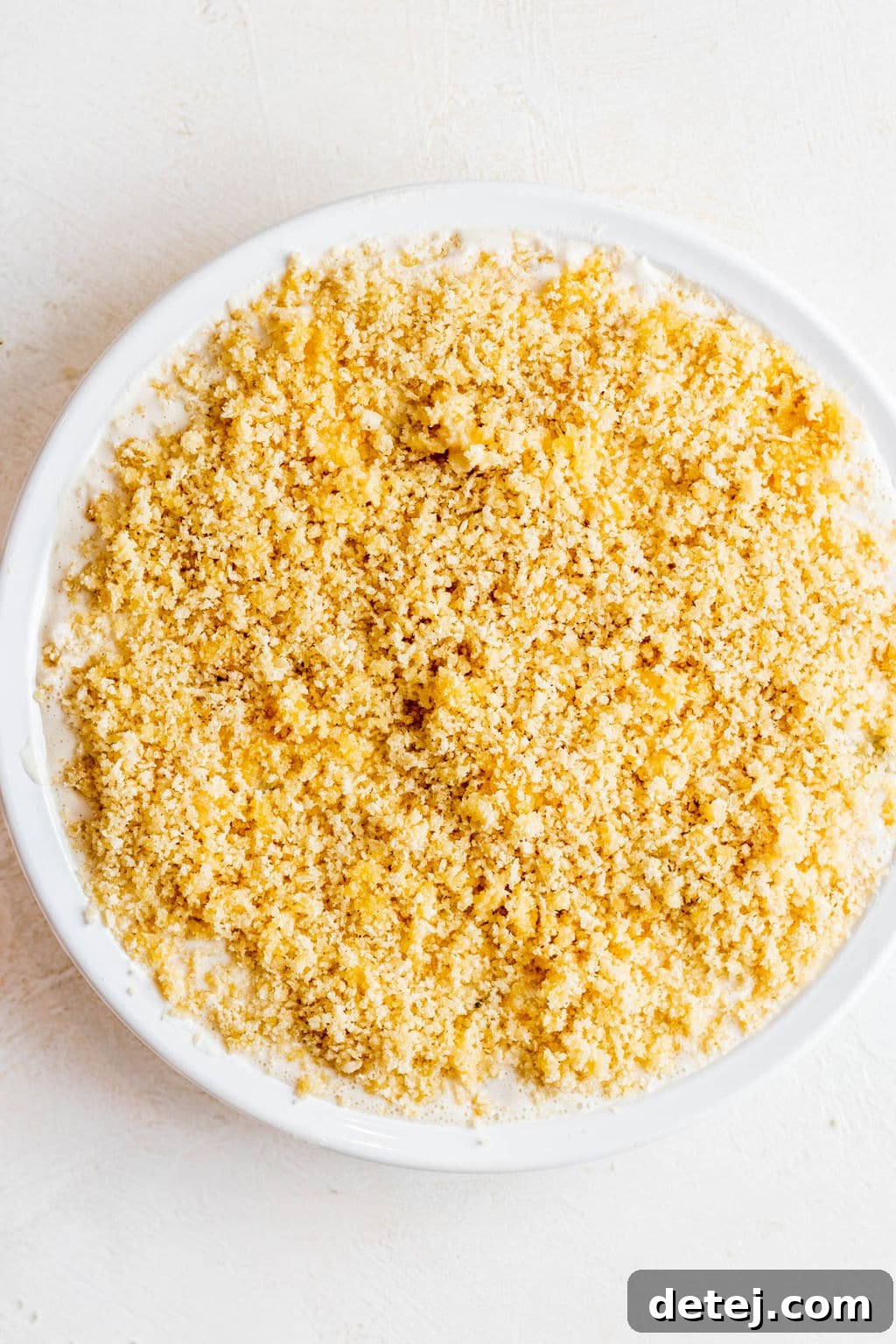 breadcrumbs on top of a white liquid in a white bowl.