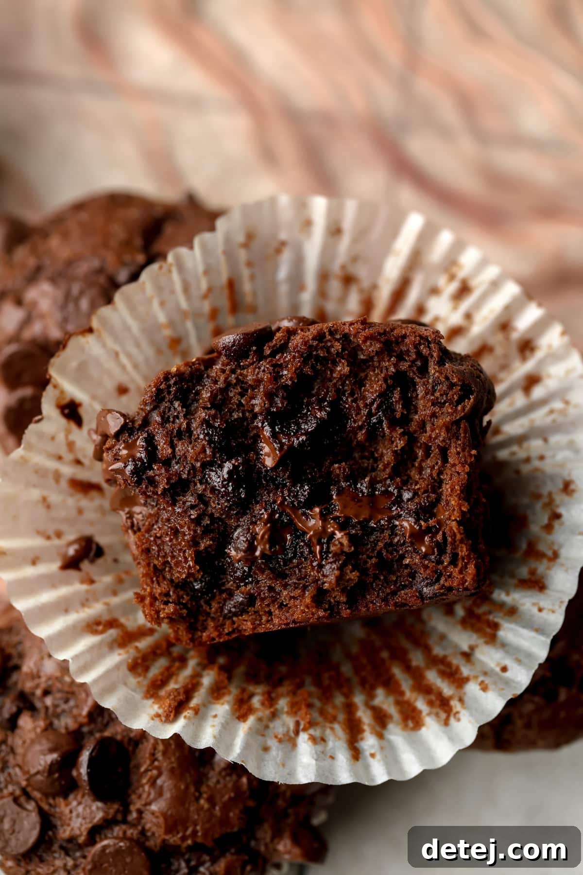 showing cut in half vegan chocolate muffin, showing gooey chocolate inside