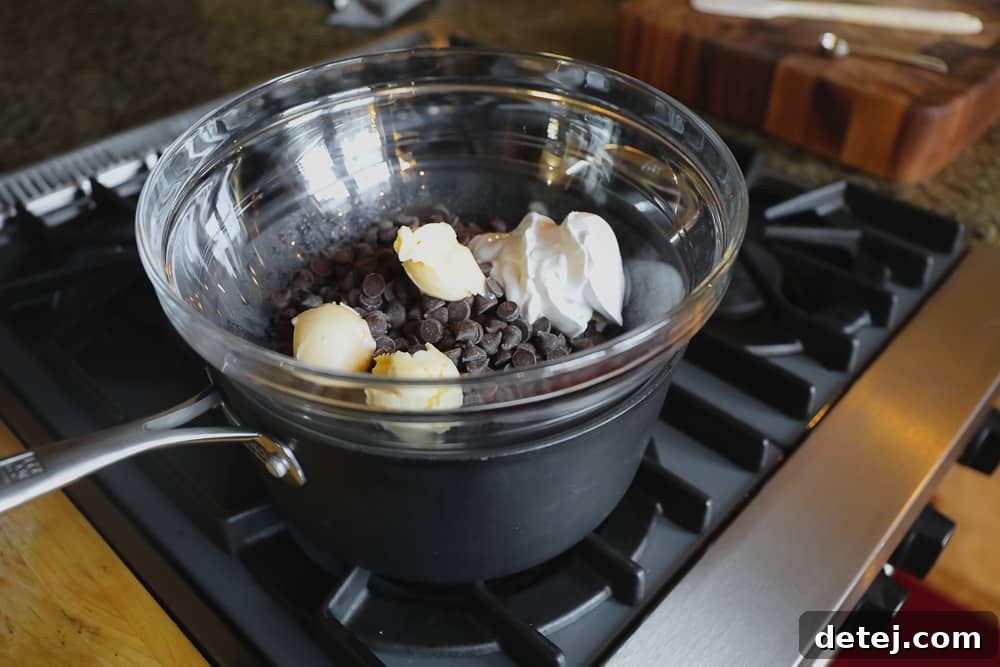 Melting vegan chocolate chips, vegan butter, and coconut cream together over a double boiler on a stove, illustrating the first step of making the truffle base.
