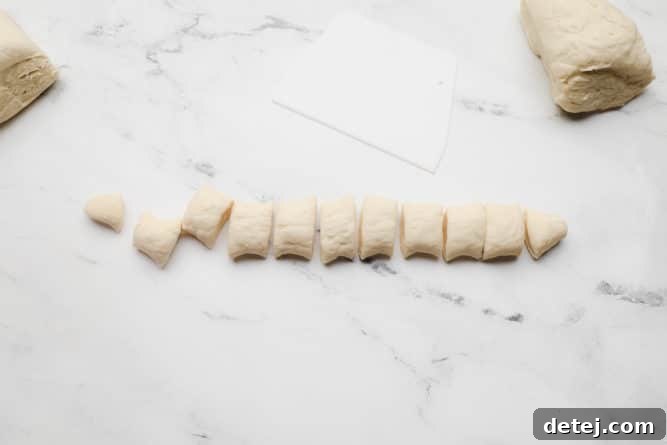 Neatly cut pieces of dough, approximately one inch in size, arranged on a white marble background.