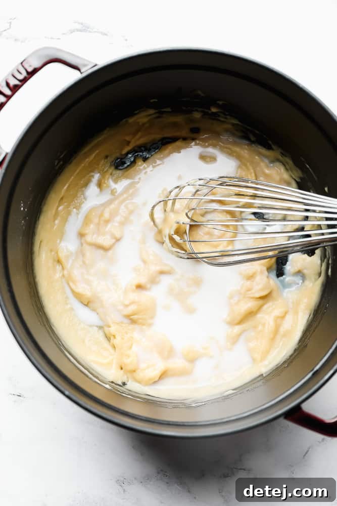 a pot with thick mixture and milk added with a whisk