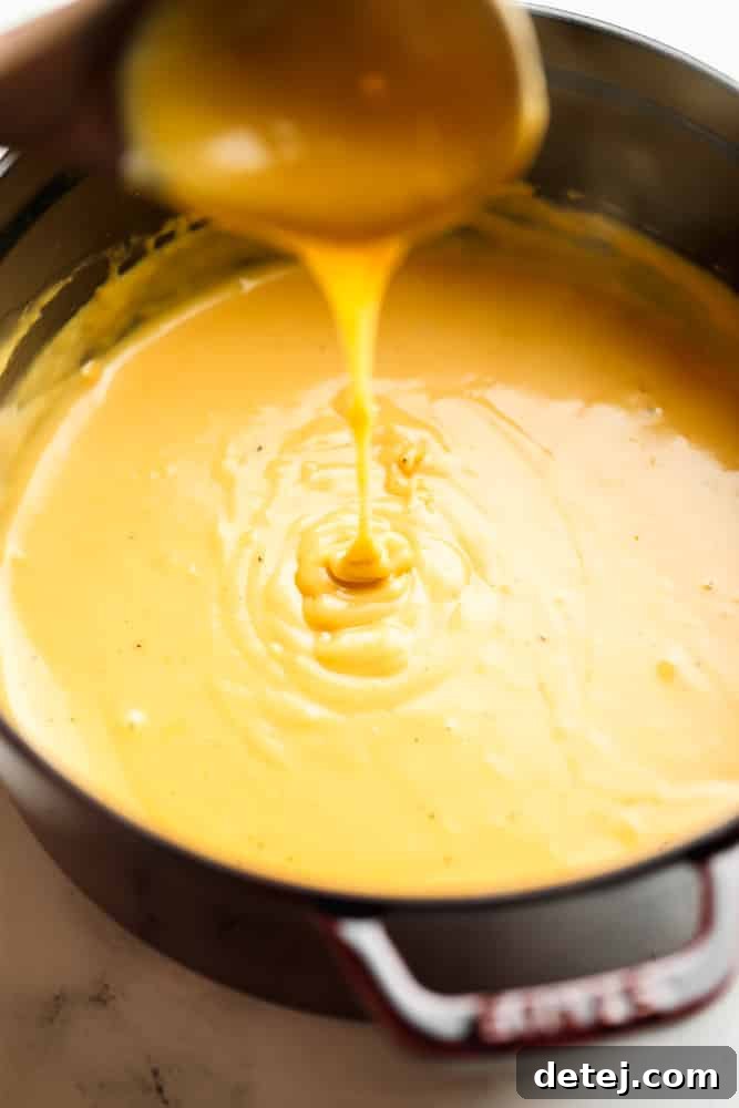 pan full of beer cheese dip, a spoon is drizzling some into the pot